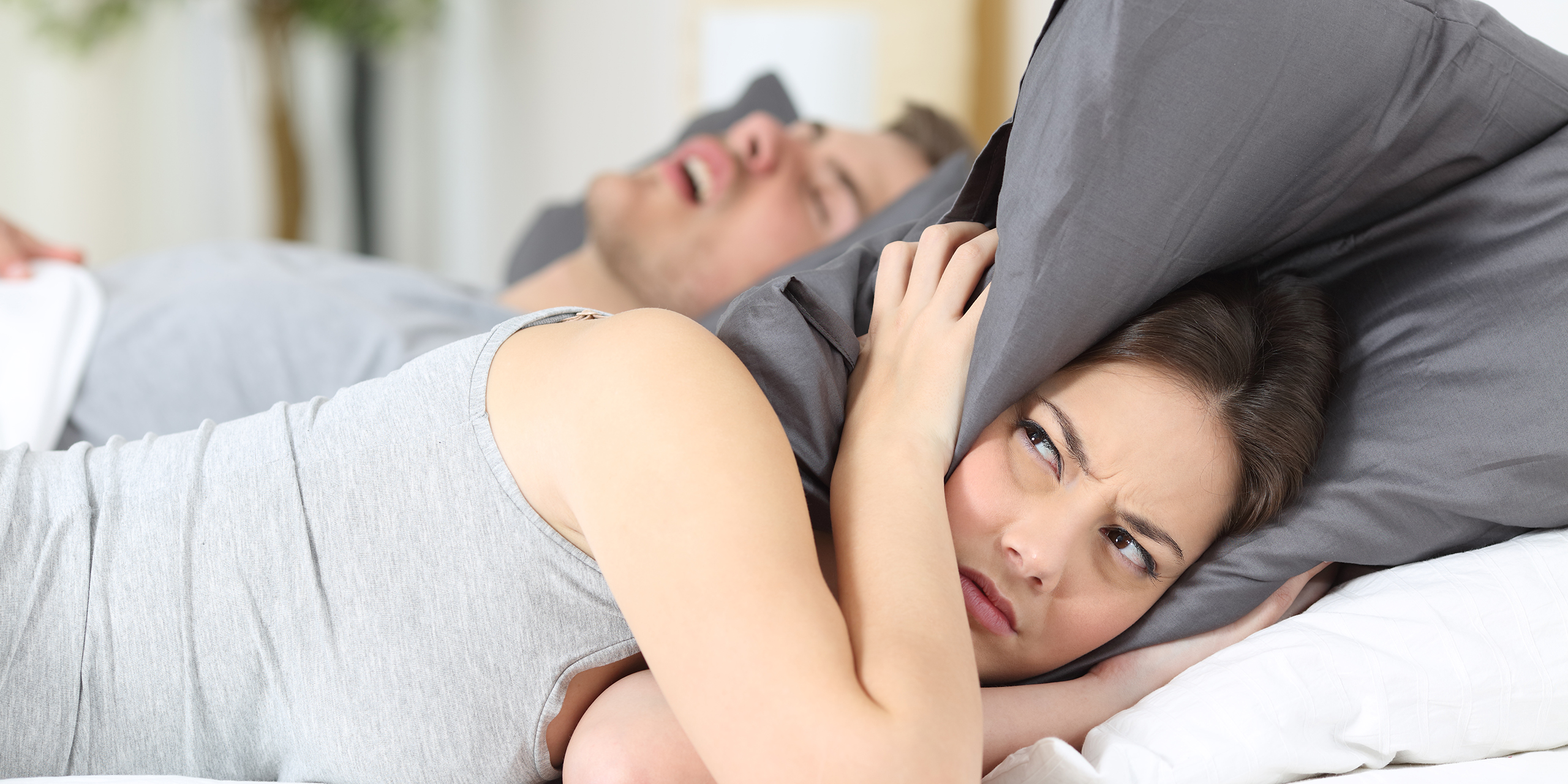 Man snoring and his wife covering ears