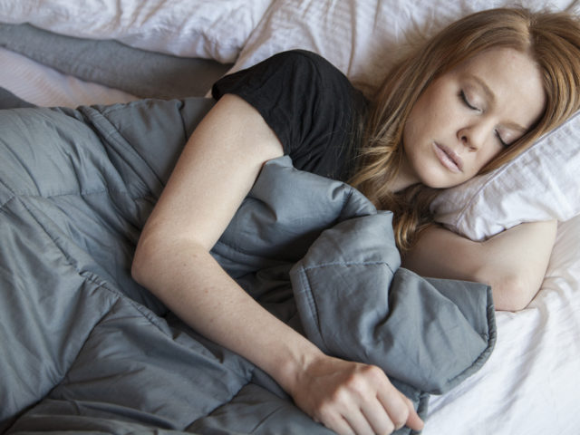Woman sleeping while using a weighted blanket