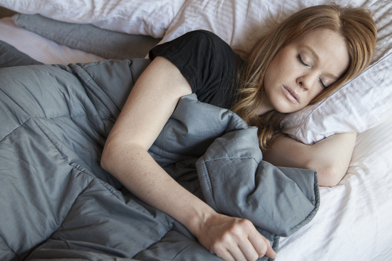 Woman sleeping while using a weighted blanket