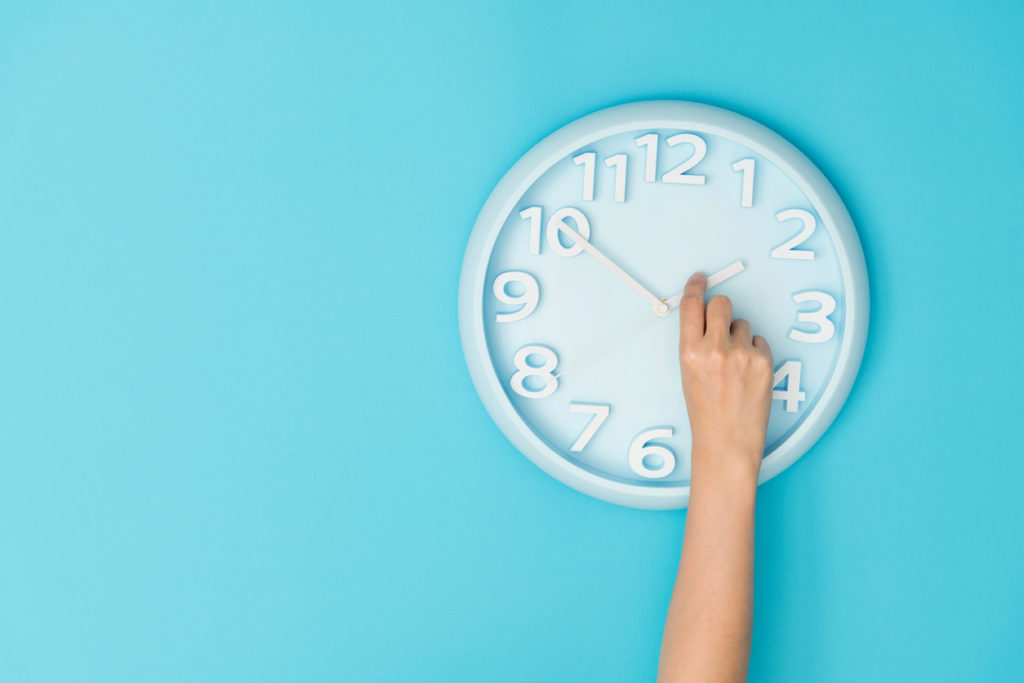 Human hand adjusting the hour clock.