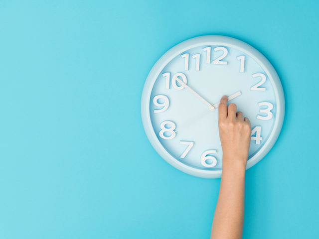 Human hand adjusting the hour clock.