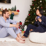 People giving gifts while sitting in front of a Christmas Tree